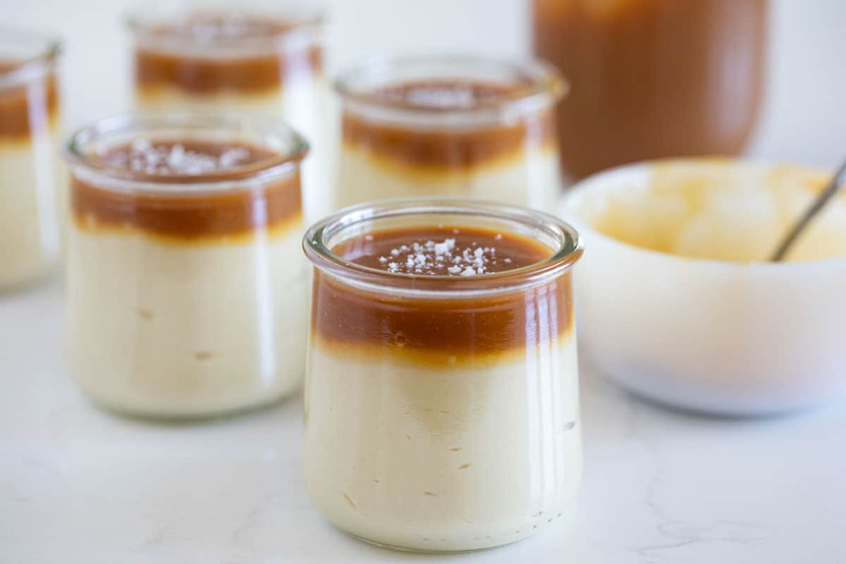 small dessert glasses with butterscotch budino with salted caramel on top.