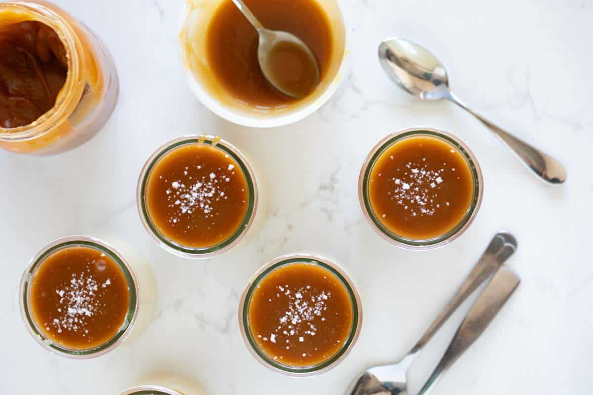 Overhead view of dessert glasses with budino topped with caramel and sea salt.