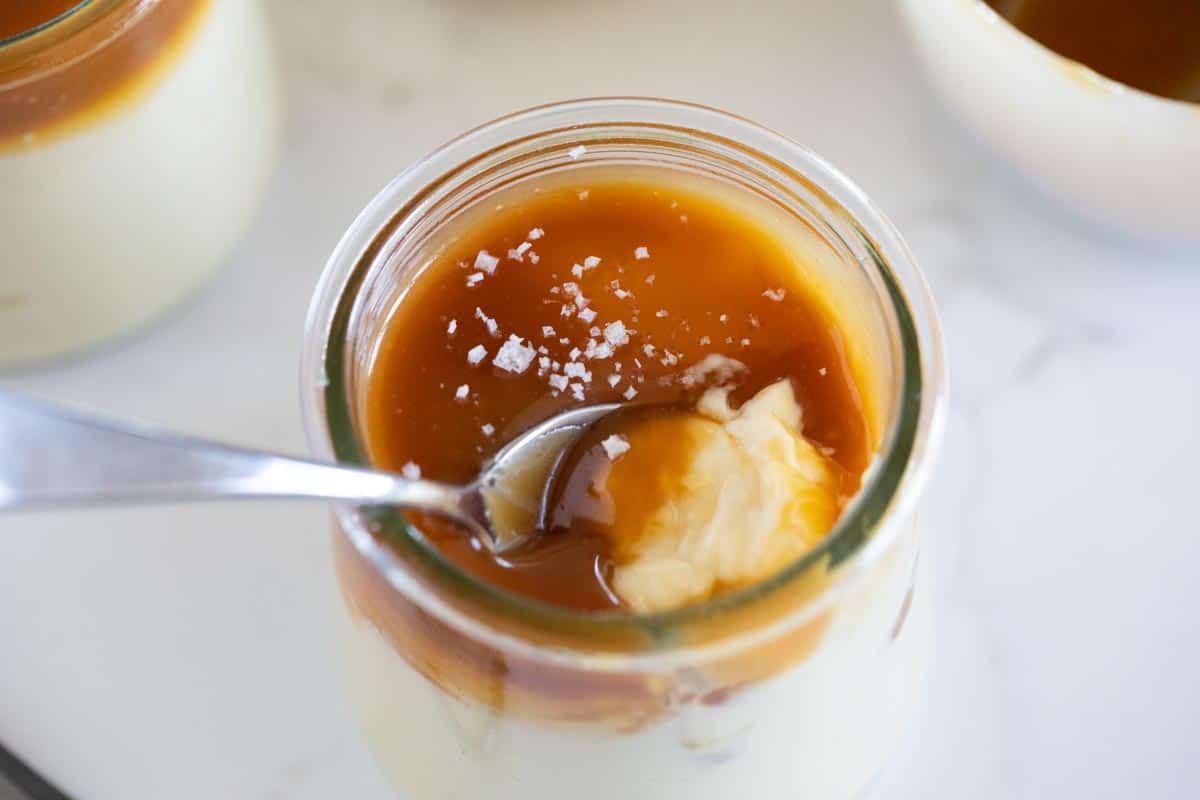 spoon in a glass of budino topped with caramel.