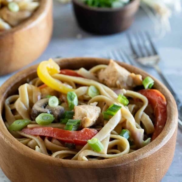 bowl with Cajun chicken pasta with ingredients in the background