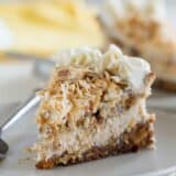 slice of carrot cake cheesecake topped with toasted coconut on a plate