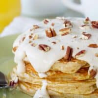 stack of carrot cake pancakes topped with maple cream cheese syrup and nuts.