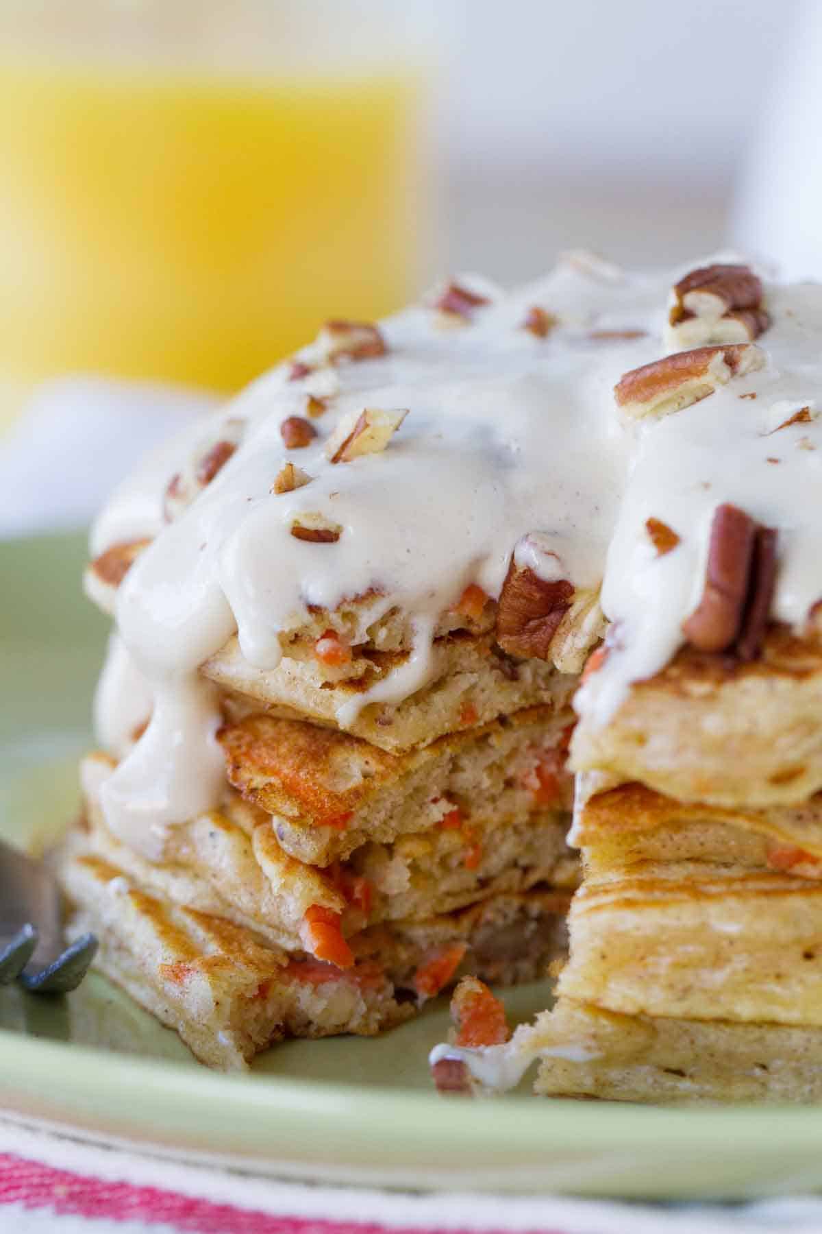 stack of carrot cake pancakes with maple cream cheese syrup with a forkful taken from it to show texture