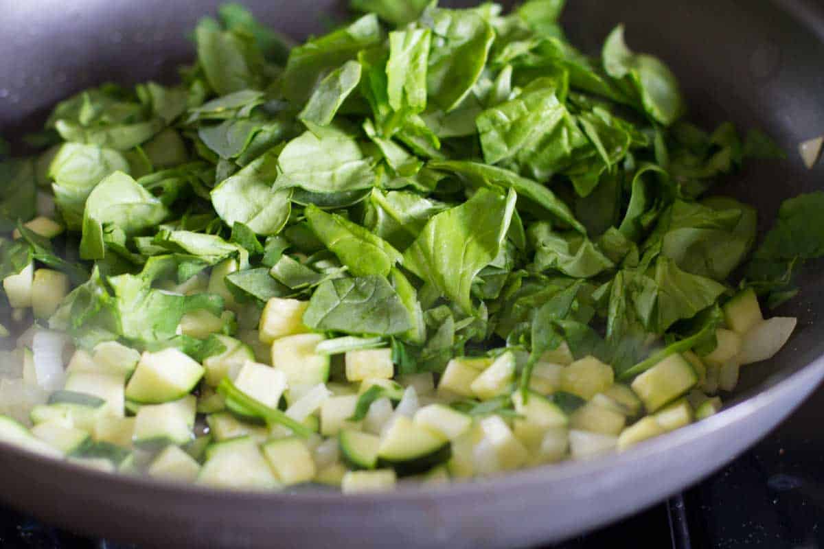 cooking down vegetables to fill tomatoes.