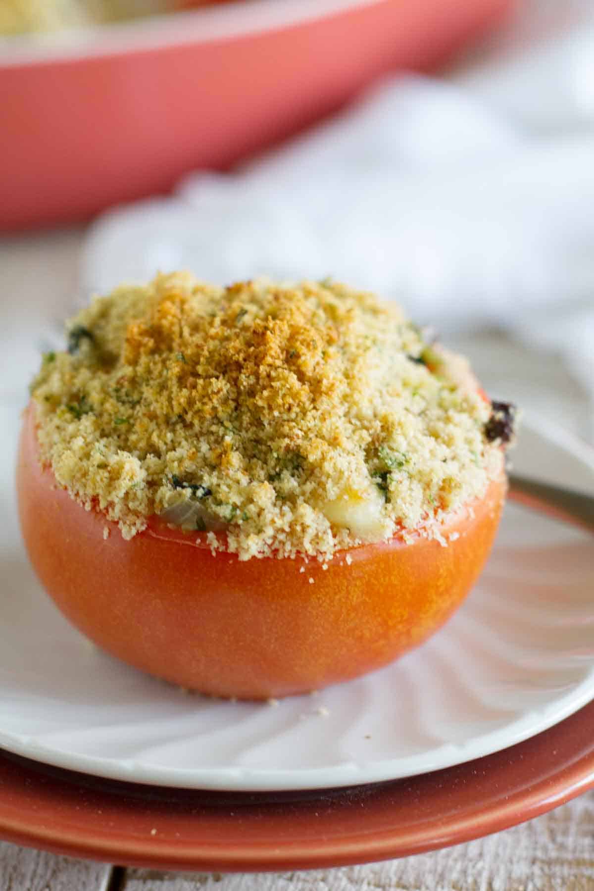 Single Cheesy Italian Stuffed Tomato on a plate.