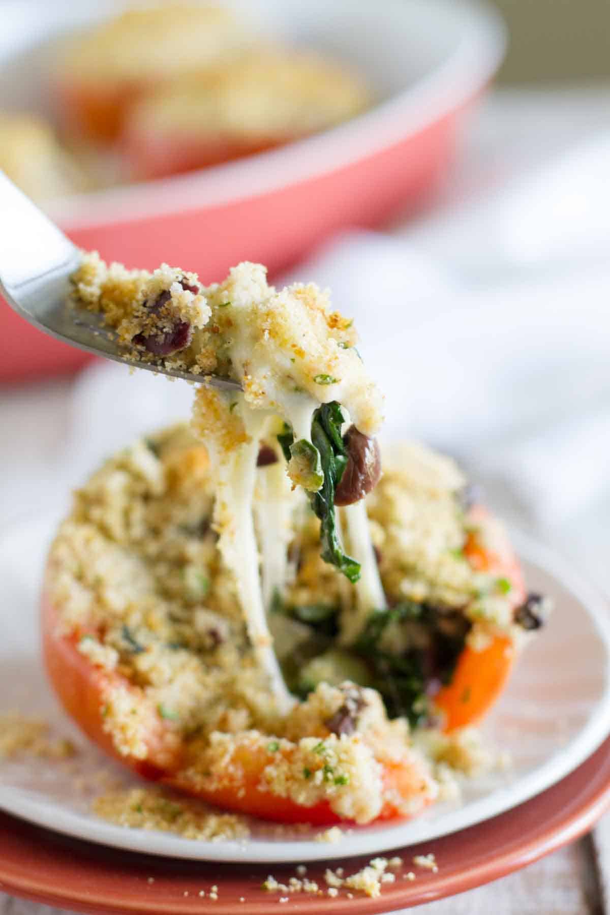 Stuffed tomato with a forkful of filling being scooped out.