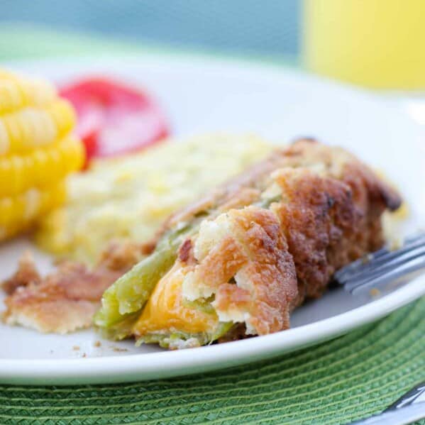 Chile relleno on a plate with a bite taken out showing the cheese.