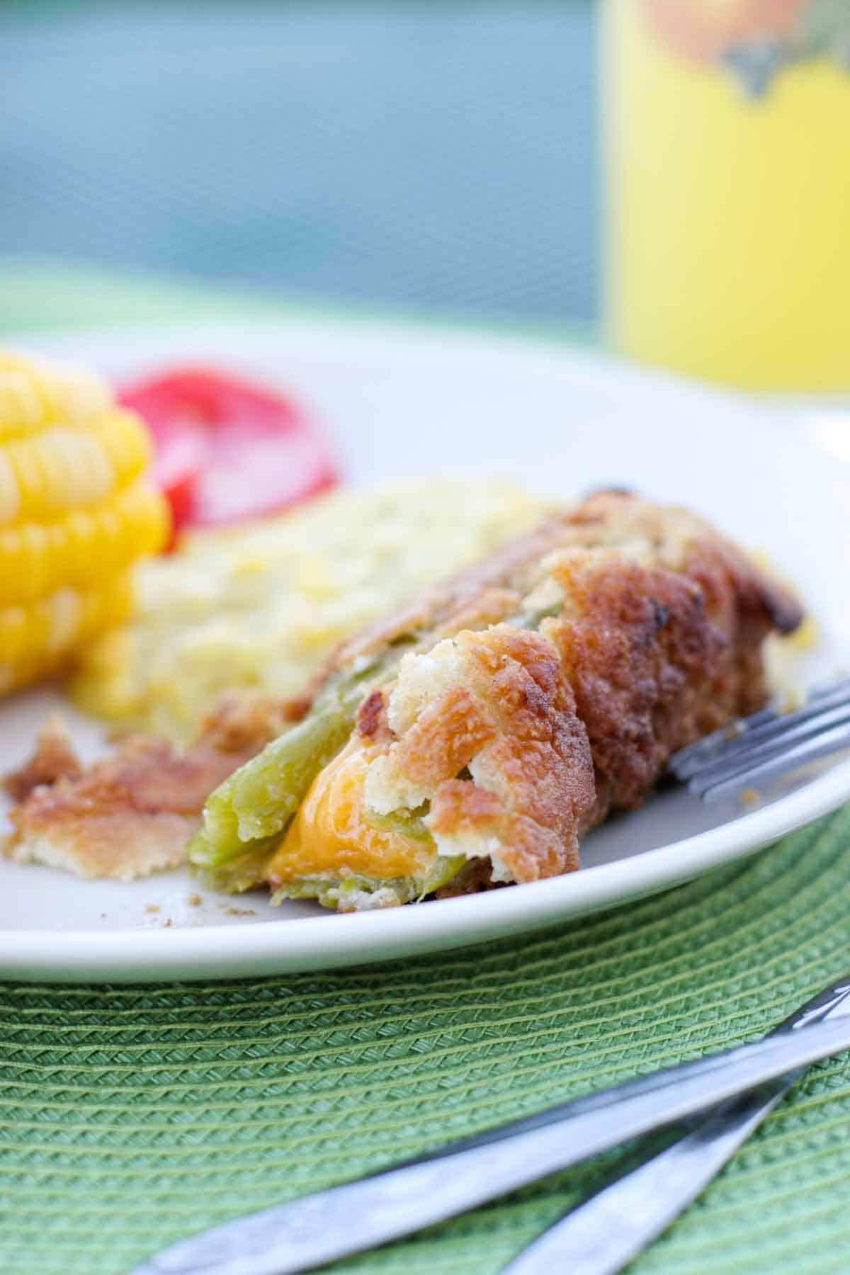 Chile relleno on a plate with a bite taken out showing the cheese.