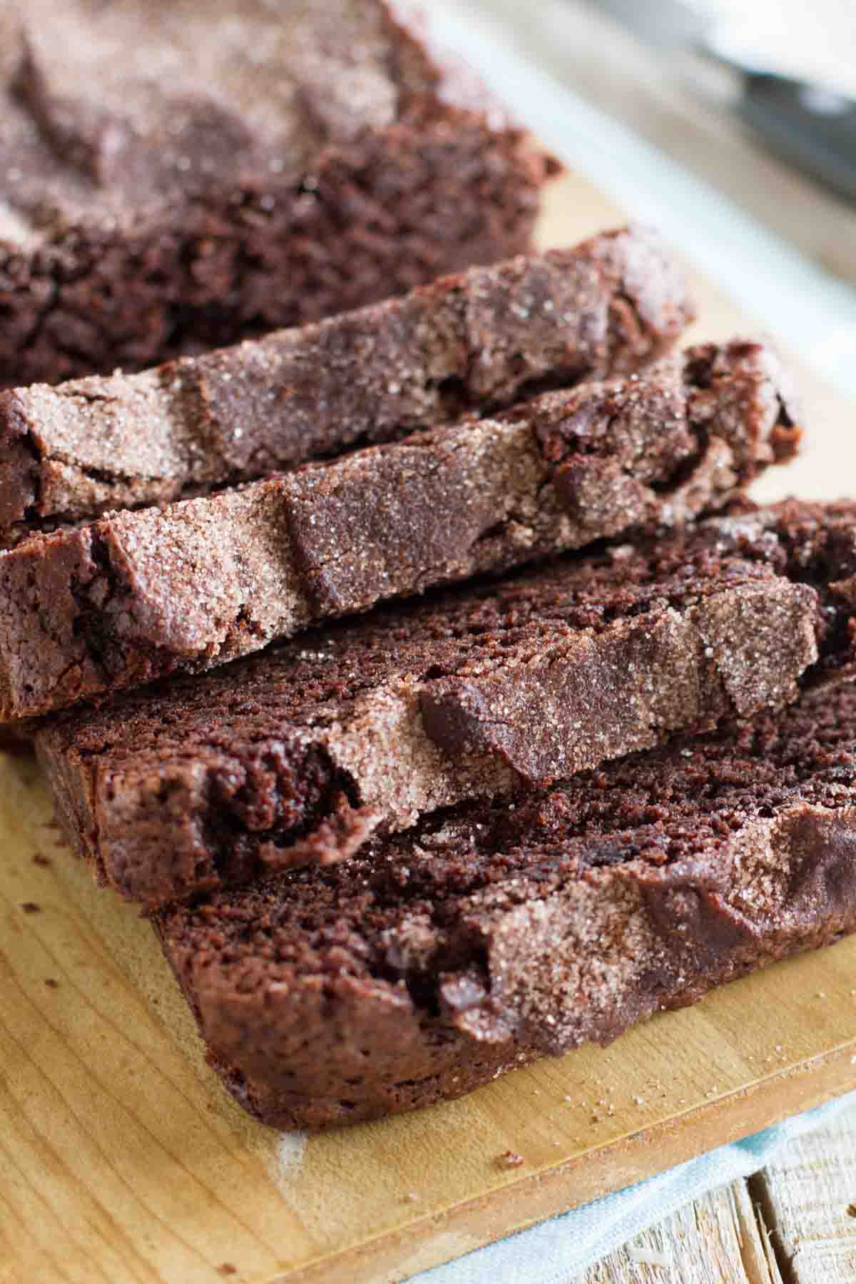 A Starbucks copycat, this Chocolate Cinnamon Bread is a rich chocolate bread with a hint of cinnamon, topped with a crunchy cinnamon sugar topping. loaf of sliced chocolate cinnamon bread on a cutting board