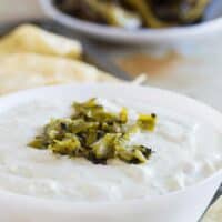 bowl filled with creamy hatch green chile dip with chopped chiles on top