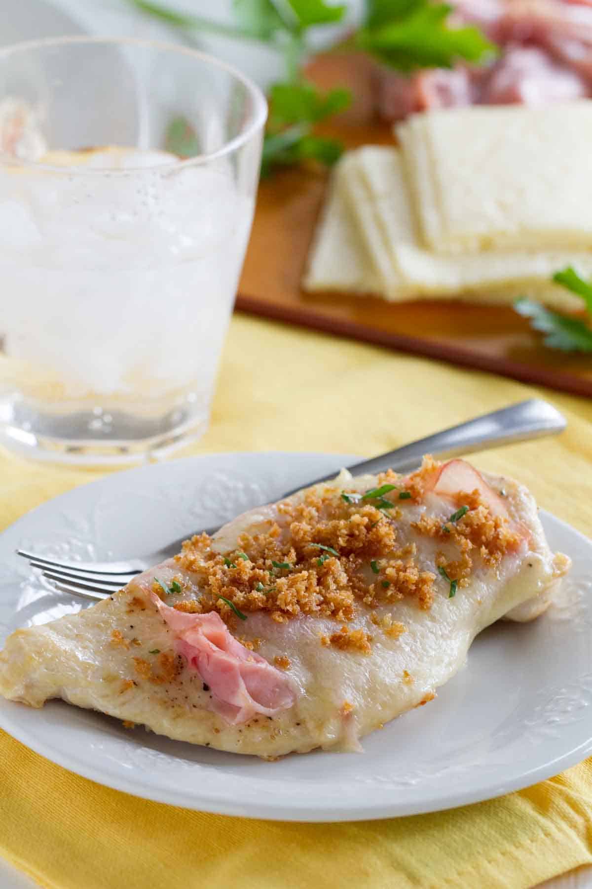 portion of chicken cordon bleu on a white plate with a fork