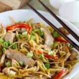 shallow bowl with egg and pork lo mein with chopsticks