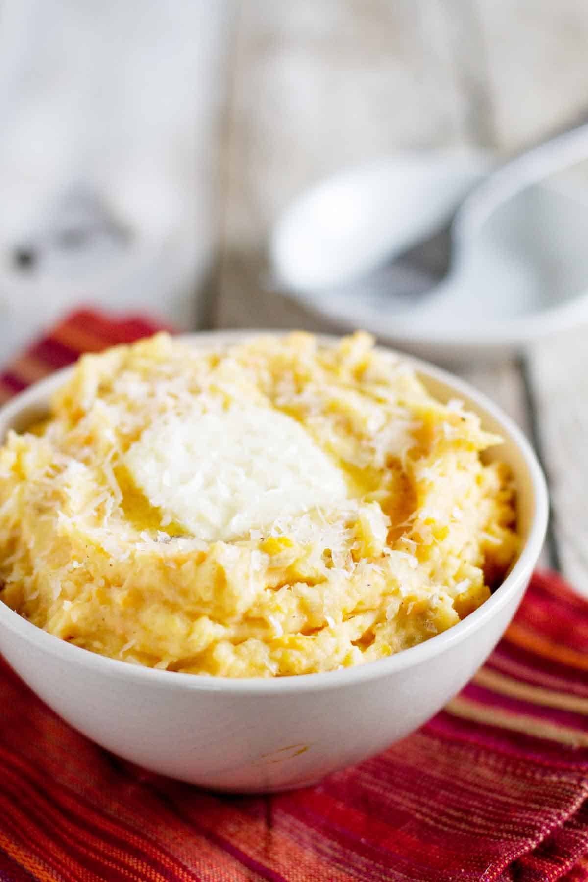 Golden Potato Mash - the addition of a sweet potato to these decadent mashed potatoes really bumps up the flavor to make this a favorite mashed potato recipe! bowl filled with Golden Potato Mash with butter and cheese on top