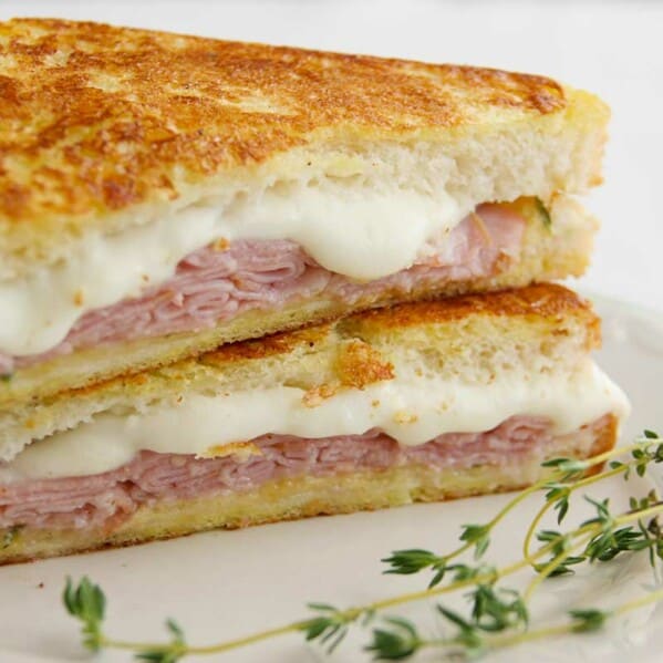 Italian Style Monte Cristos stacked on a plate with thyme on the side