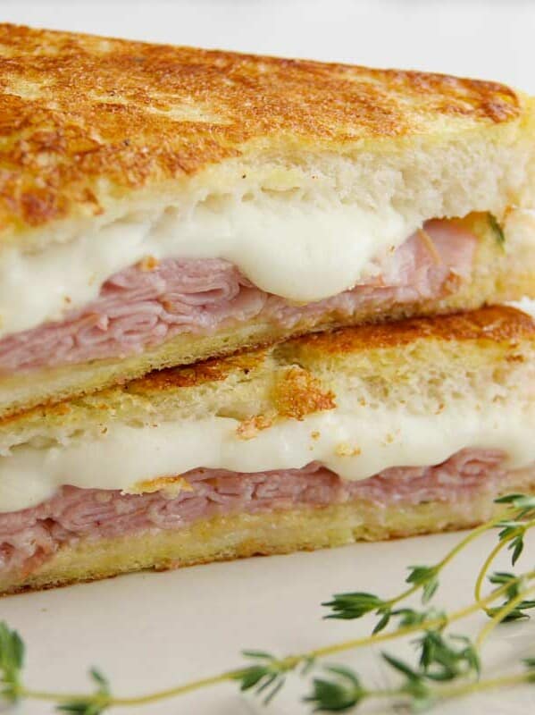 Italian Style Monte Cristos stacked on a plate with thyme on the side