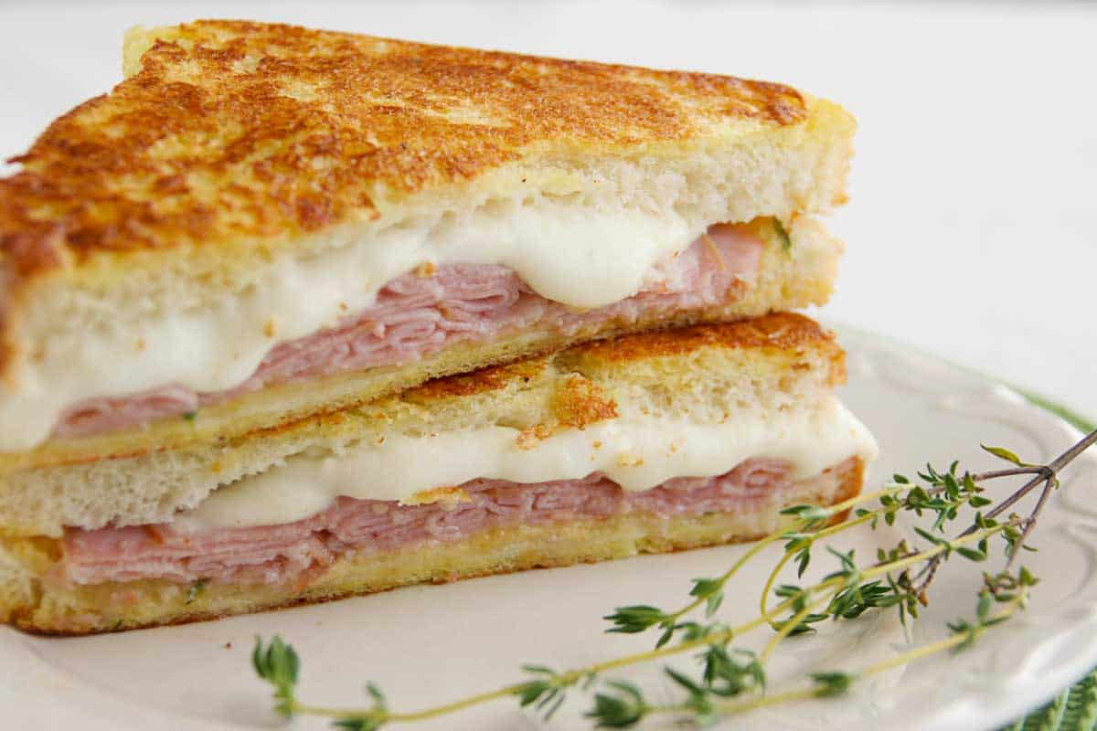 Italian Style Monte Cristos stacked on a plate with thyme on the side