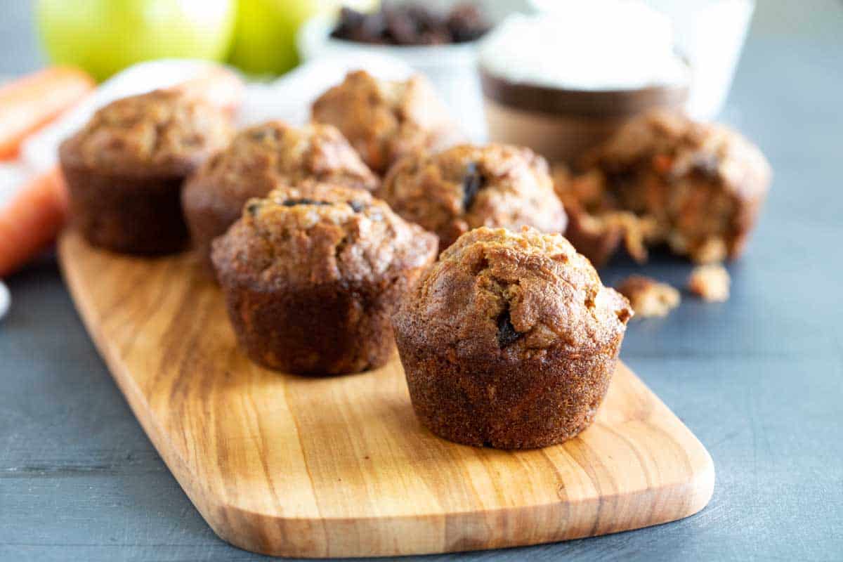 Filled with all kinds of good for ingredients, these Morning Glory Muffins are the perfect way to start the morning! Carrots, apples, raisins, coconut, and nuts fill these hearty and tasty muffins. Morning glory muffins on a wooden board
