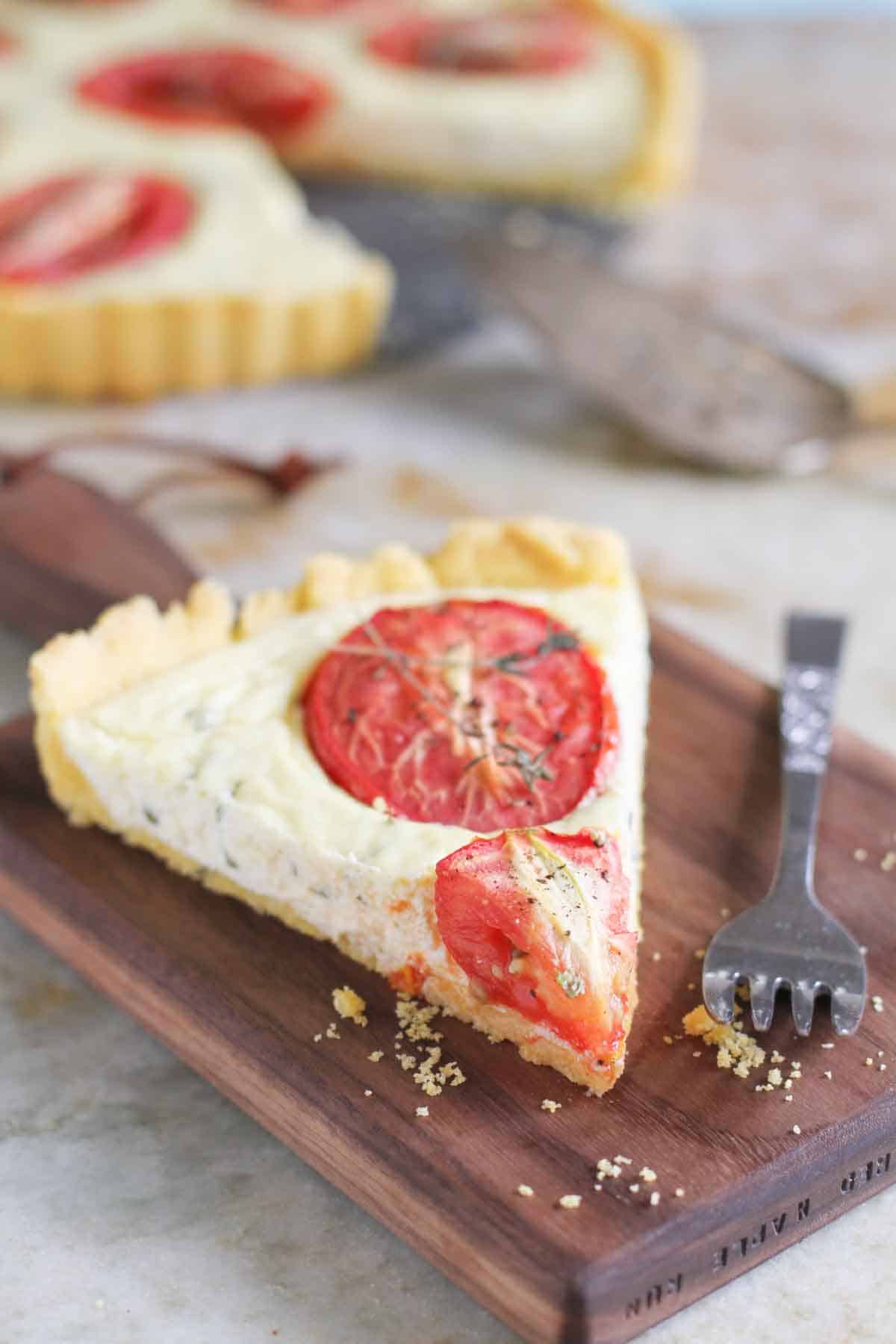 slice of polenta crust tomato tart on a cutting board with a fork next to it