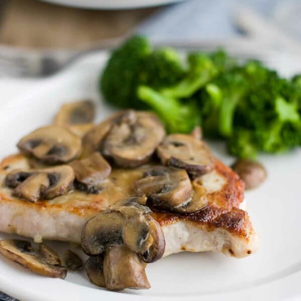pork chop on a plate covered in dijon mushrooms with broccoli