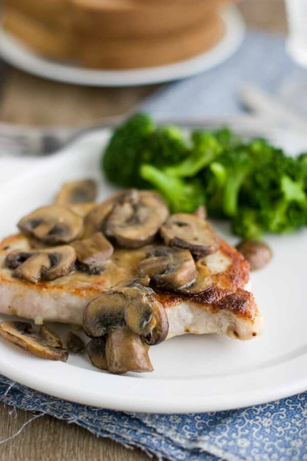 pork chop on a plate covered in dijon mushrooms with broccoli