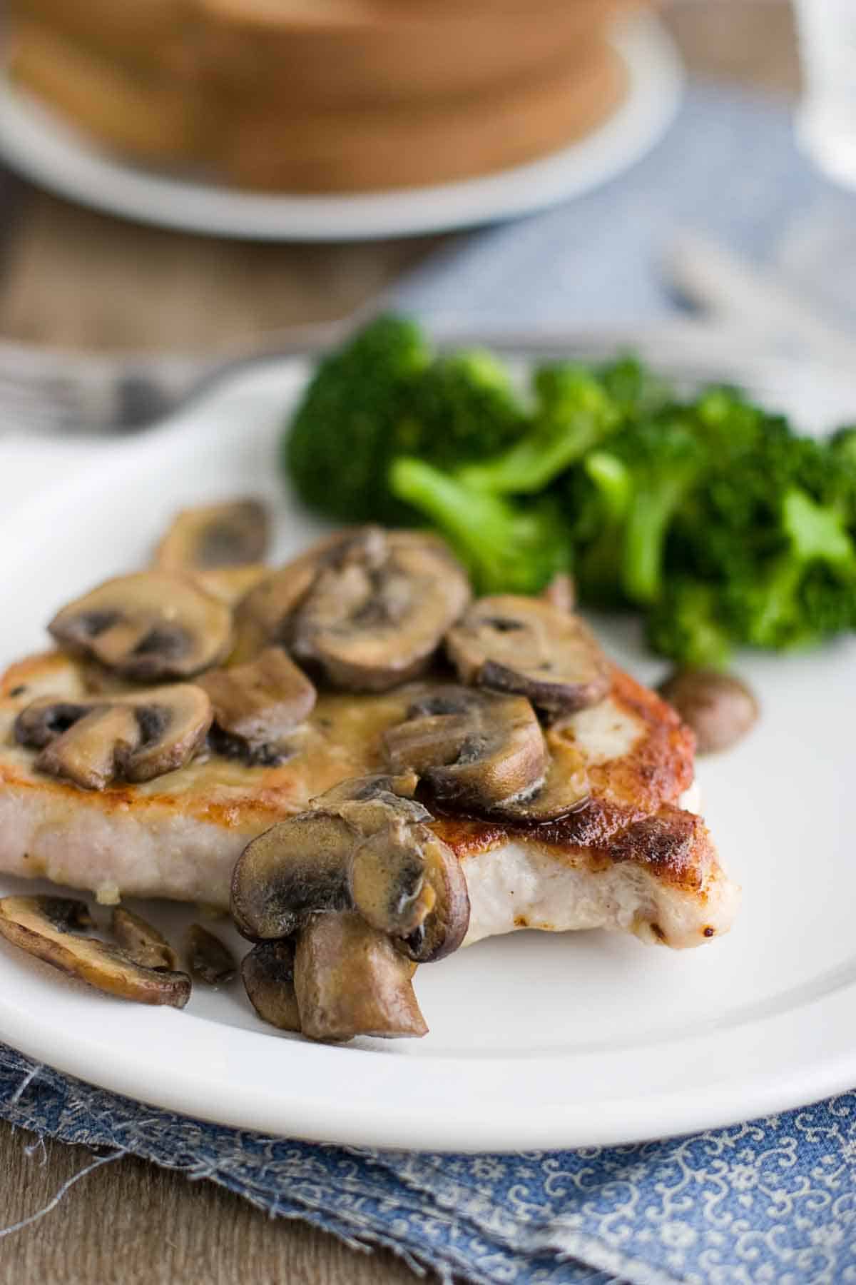 Get dinner on the table in minutes with these easy skillet cooked pork chops with dijon mushrooms. pork chop on a plate covered in dijon mushrooms with broccoli