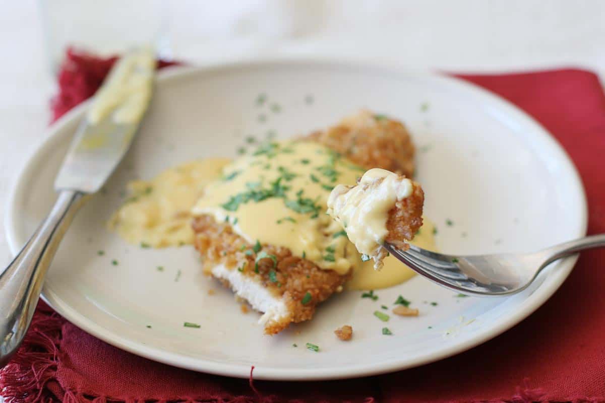 Pretzel Crusted Chicken on a plate with a bite on a fork with sauce