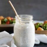 mason jar of homemade ranch dressing with salads in the background