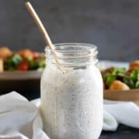 mason jar of homemade ranch dressing with salads in the background