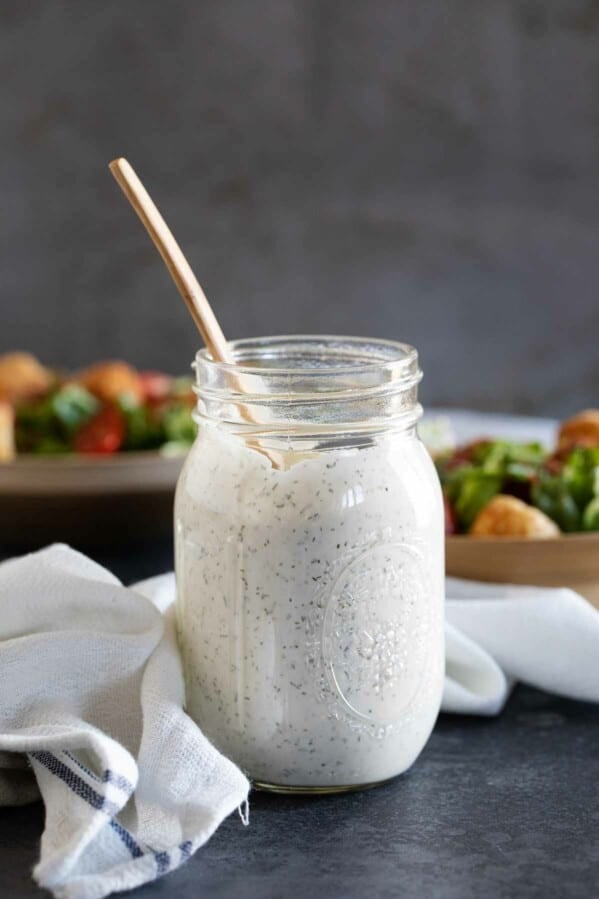 mason jar of homemade ranch dressing with salads in the background