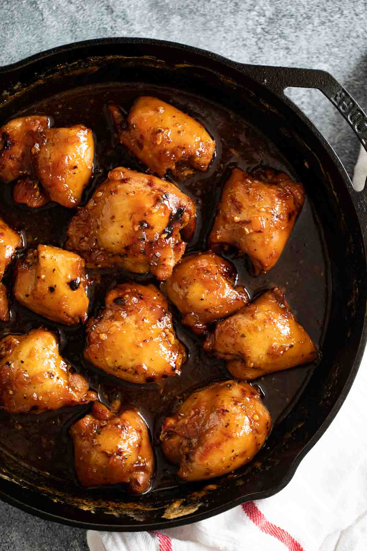 overhead view of shoyu chicken in a cast iron pan with a dishtowel.