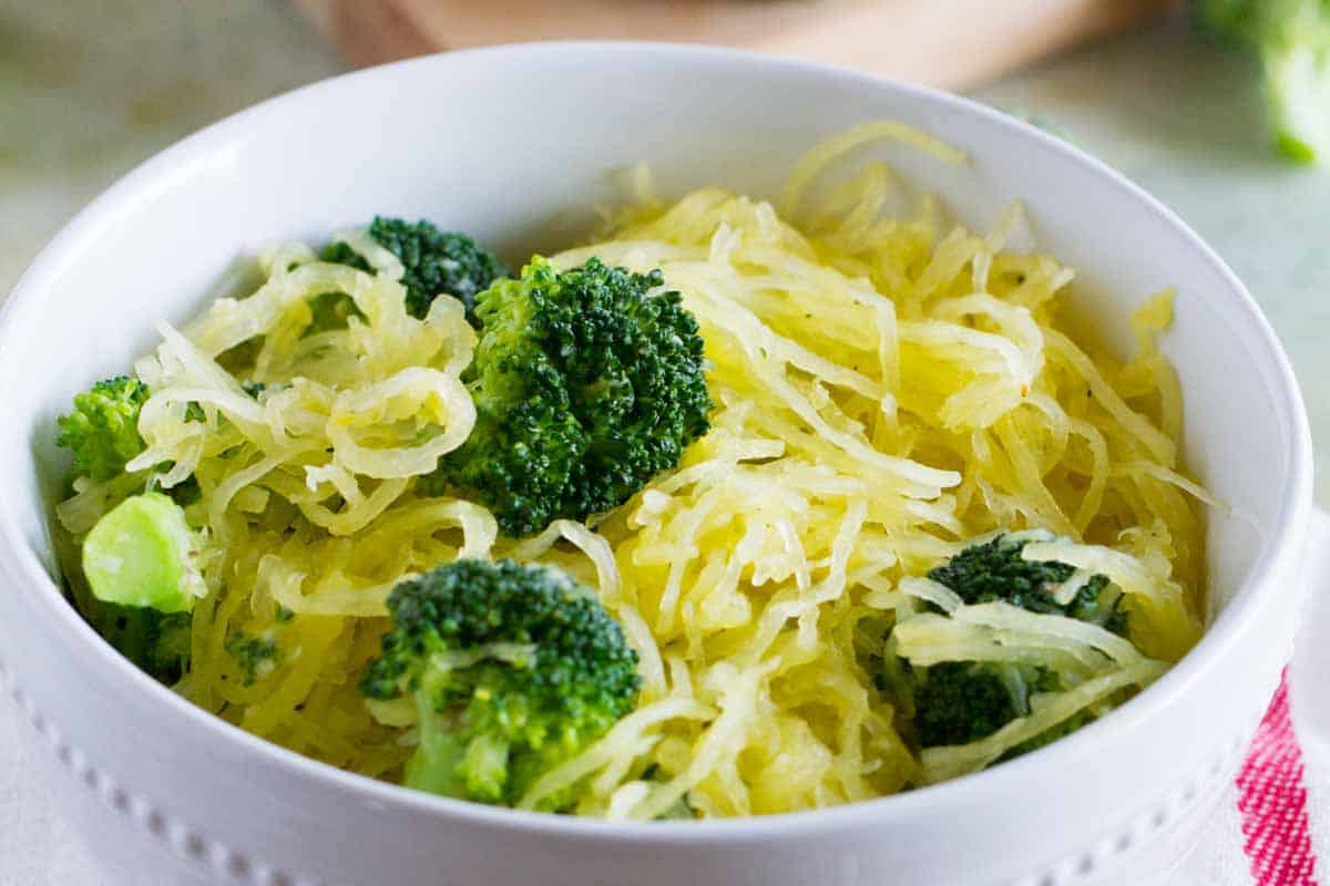 Close up of a bowl of spaghetti squash and broccoli.