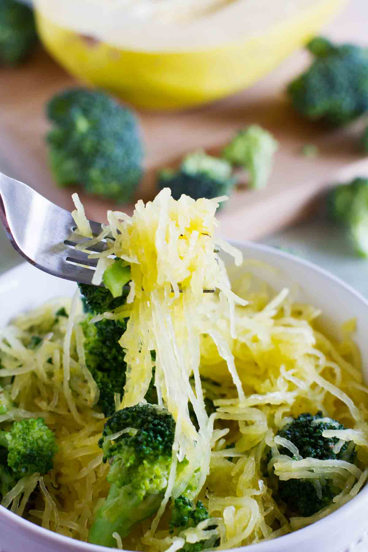 bowl of spaghetti squash with broccoli with a forkful being taken from it.