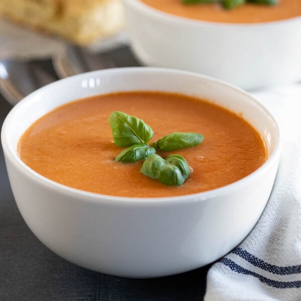 bowl of creamy tomato basil soup topped with fresh basil.