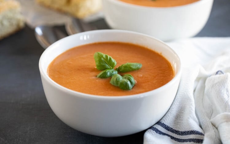 bowl of creamy tomato basil soup topped with fresh basil.