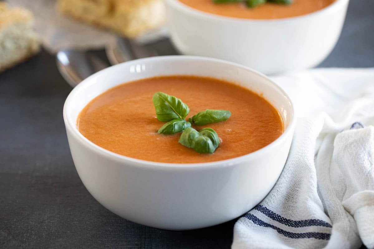 bowl of creamy tomato basil soup topped with fresh basil.