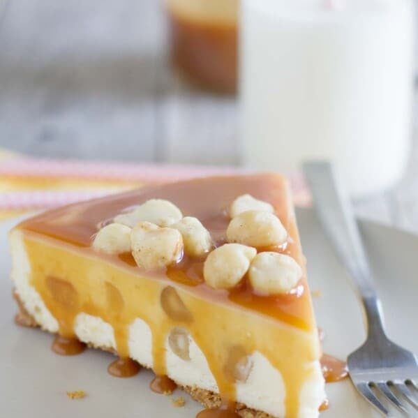 slice of white chocolate cheesecake covered in caramel and topped with macadamia nuts