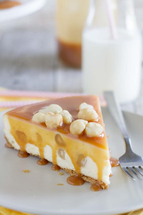 slice of white chocolate cheesecake covered in caramel and topped with macadamia nuts