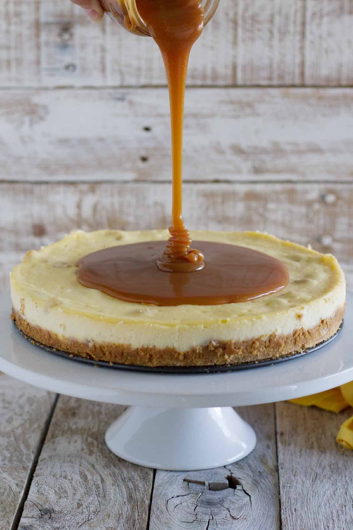 pouring caramel on top of a white chocolate cheesecake