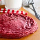 XL Red Velvet Cookie on a cutting board with milk behind