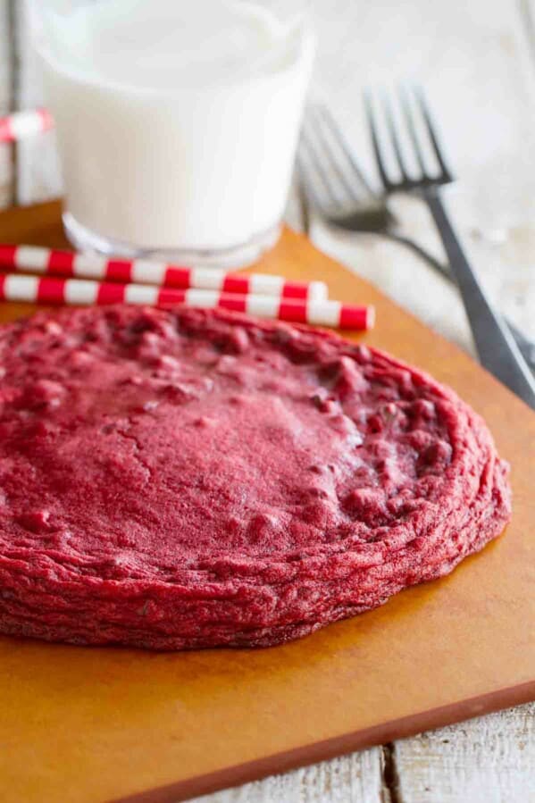 XL Red Velvet Cookie on a cutting board with milk behind