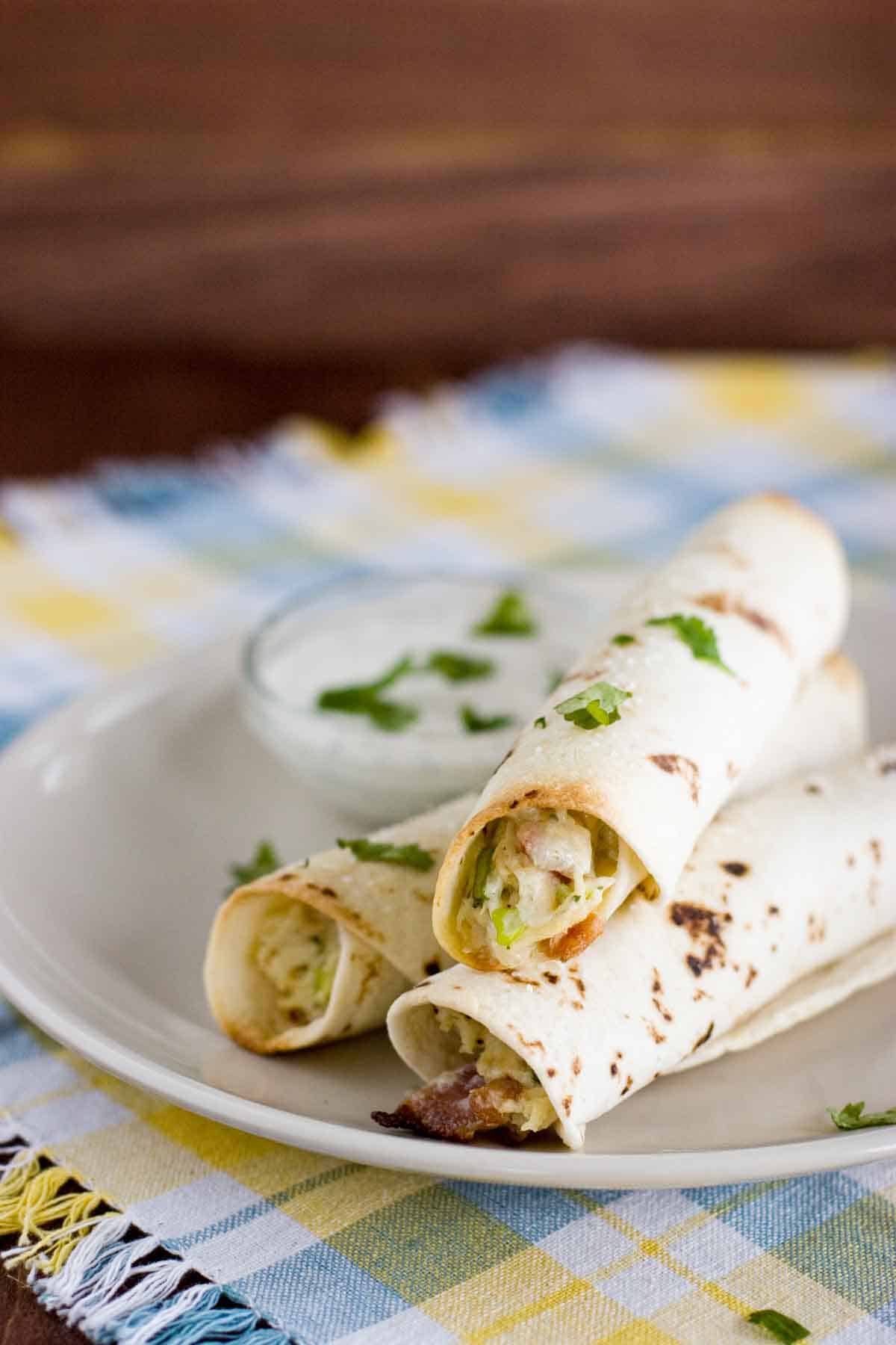 3 Baked Chicken Bacon Ranch Taquitos on a plate with dipping sauce.