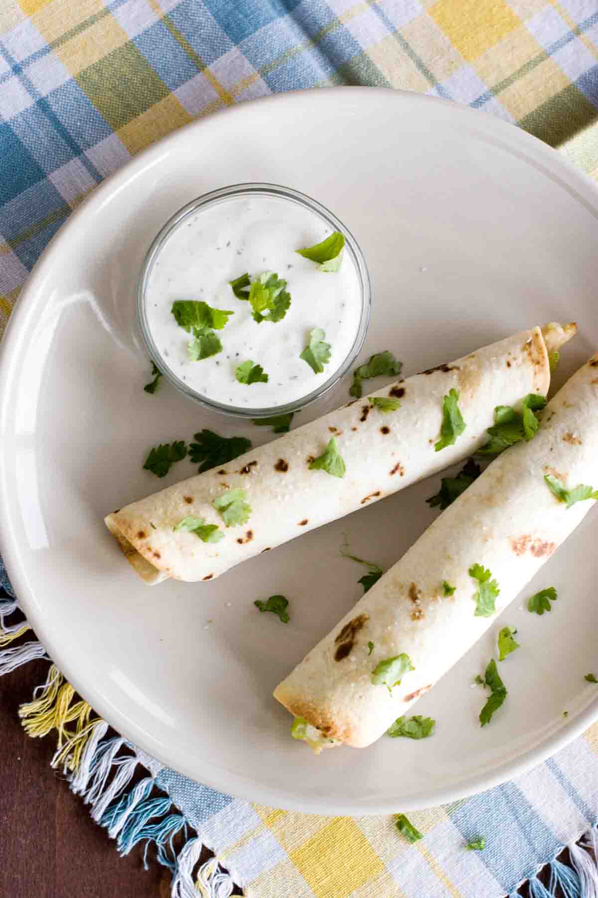 Two Baked Chicken Bacon Ranch Taquitos sprinkled with cilantro.