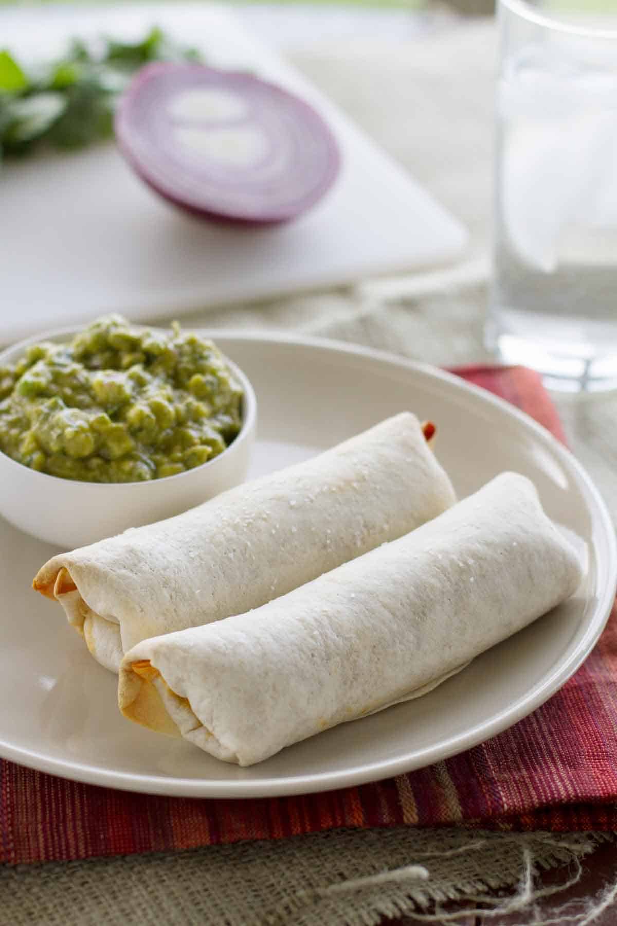 Two baked Mexican egg rolls with Enchilada Guacamole