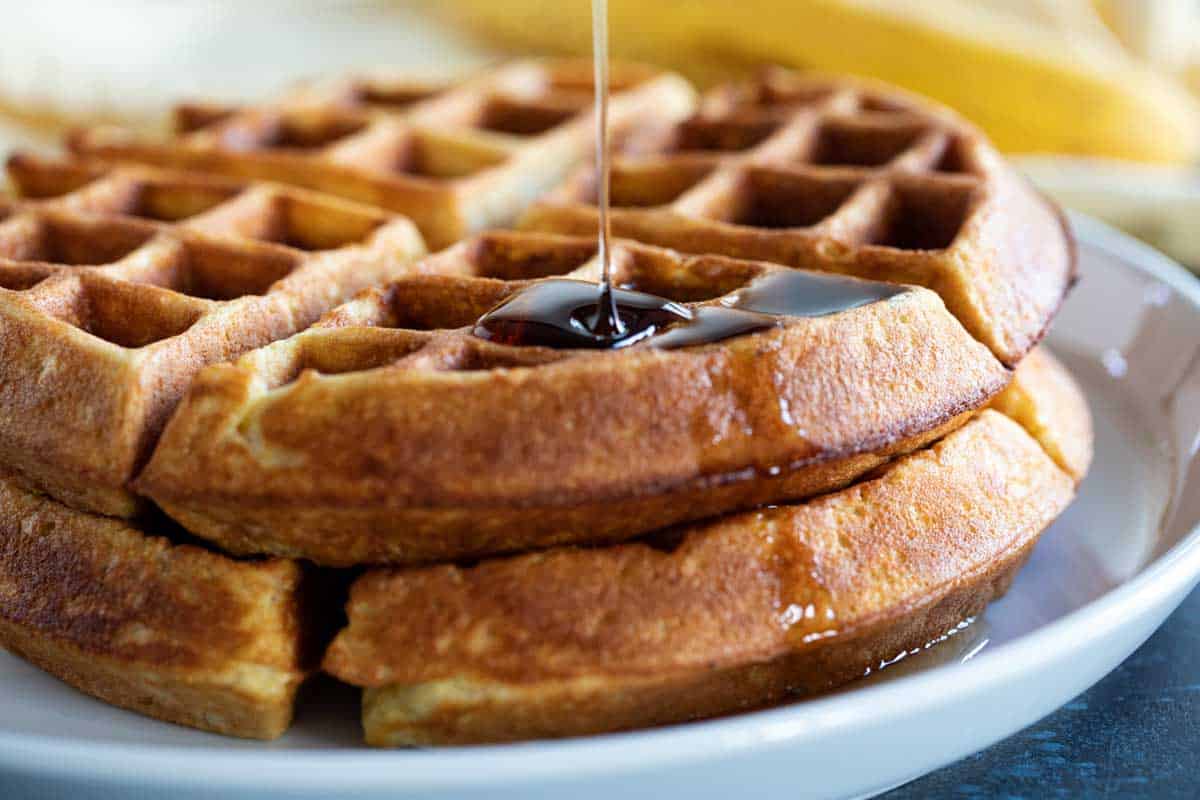 stack of two banana waffles with syrup being poured on top.