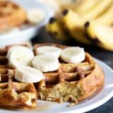 Banana Waffle topped with fresh bananas with a bite taken from it to show texture