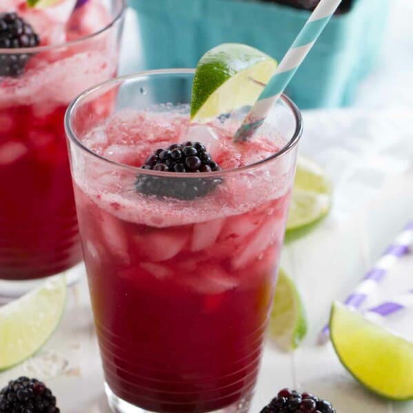 glass of blackberry lime soda topped with fresh blackberry