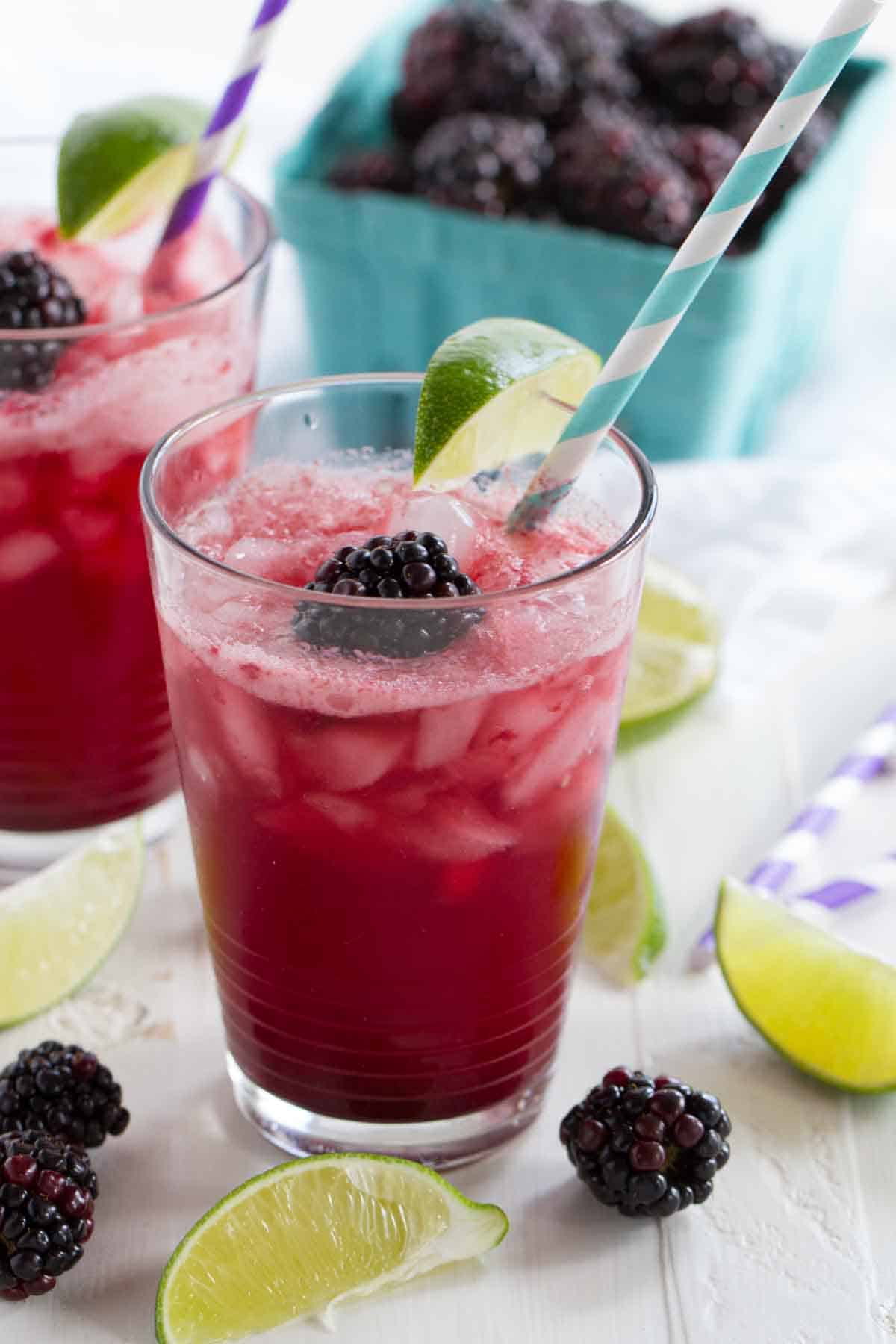 glass of blackberry lime soda topped with fresh blackberry