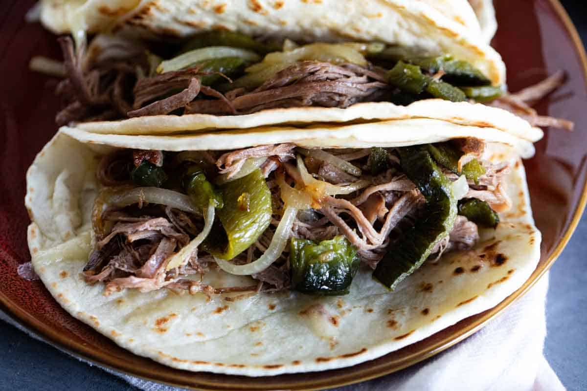 Brisket tacos with poblano peppers and onions on flour tortillas.