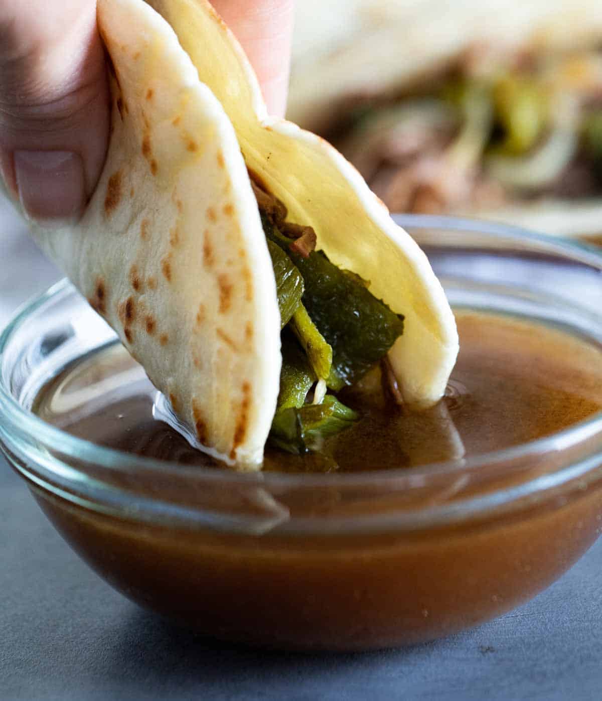 Dipping brisket tacos into broth.