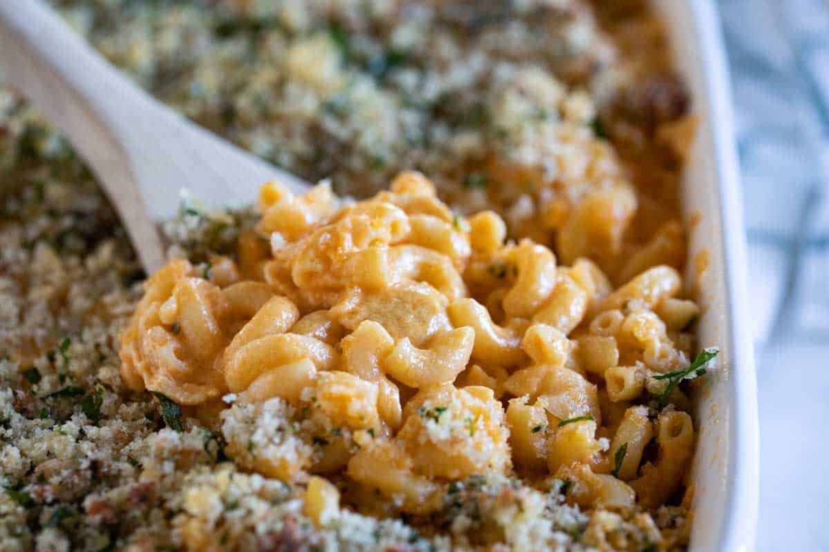 wooden spoon full of Buffalo Chicken Mac and Cheese in a baking dish